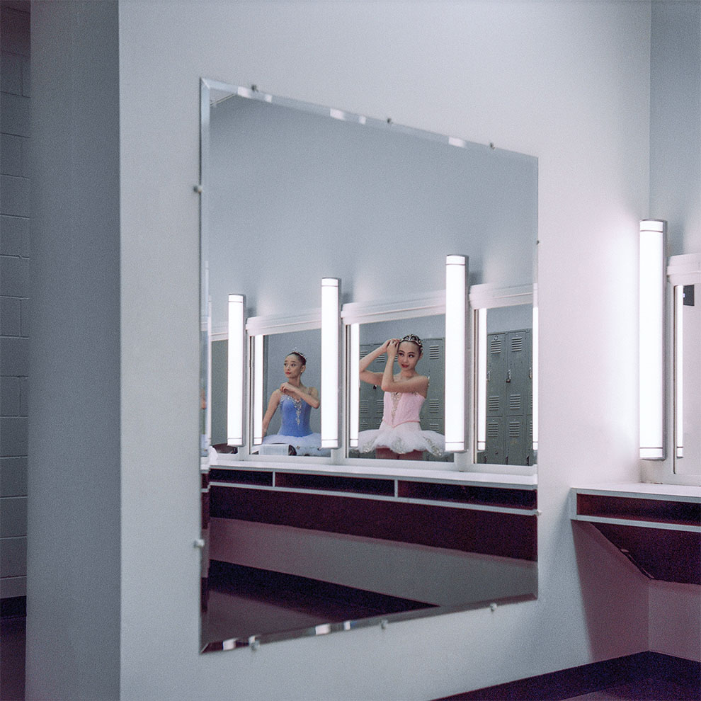 ballerina in mirror in the dressing room backstage fixes her hair. 