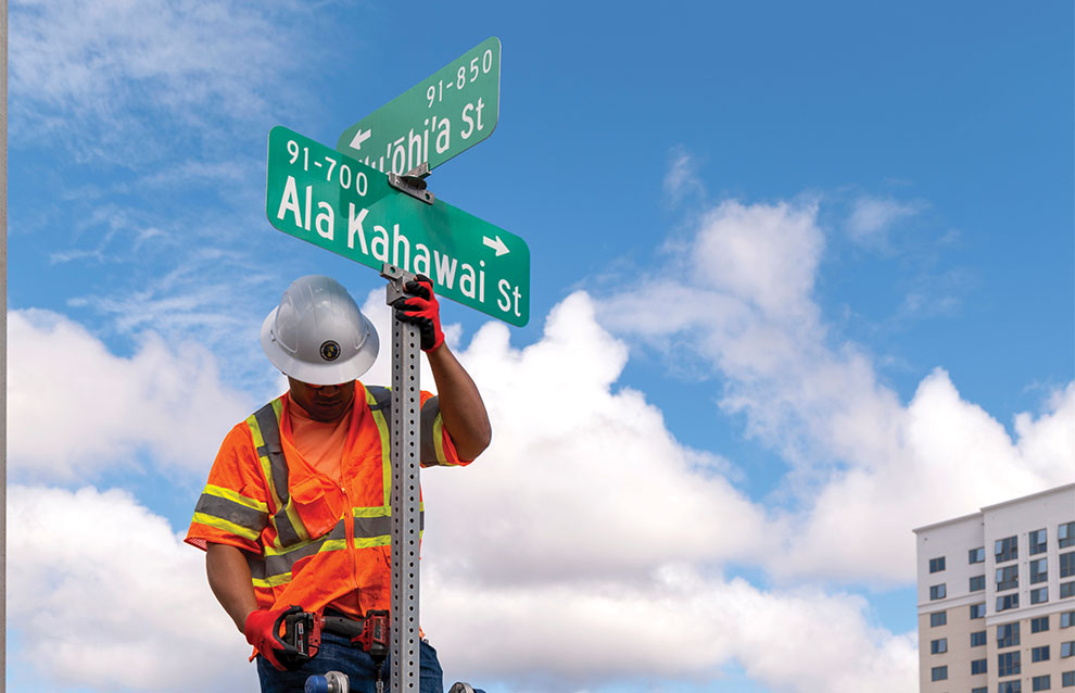 a person in safety gear fixing a street sign