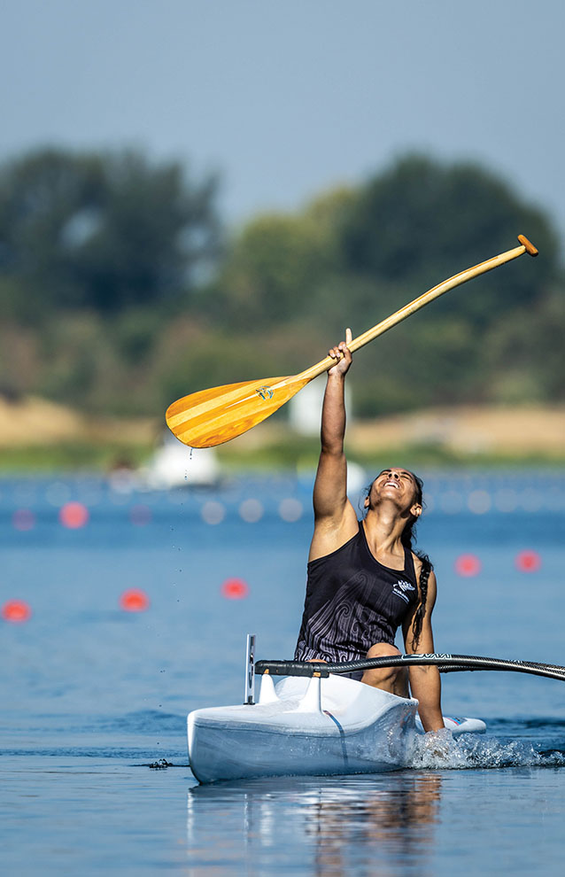 a person in a canoe holding a paddle in the air to express joy in victory