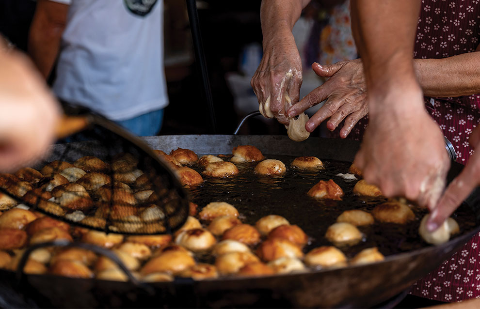 a closup of a wok filled with oil and balls of bread frying