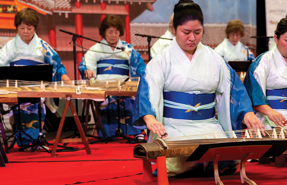 a group of people playing string instruments on the ground