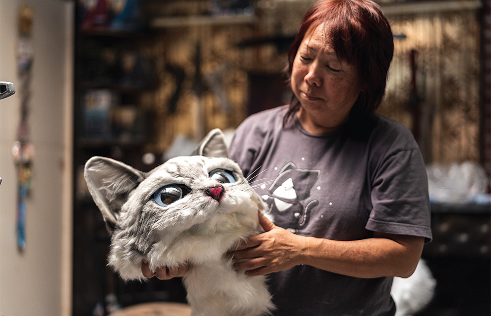 a person holding up the head of a cat costume