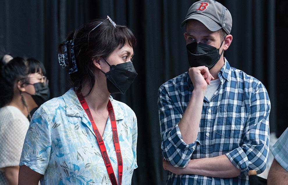 two people wearing face masks talking to each other