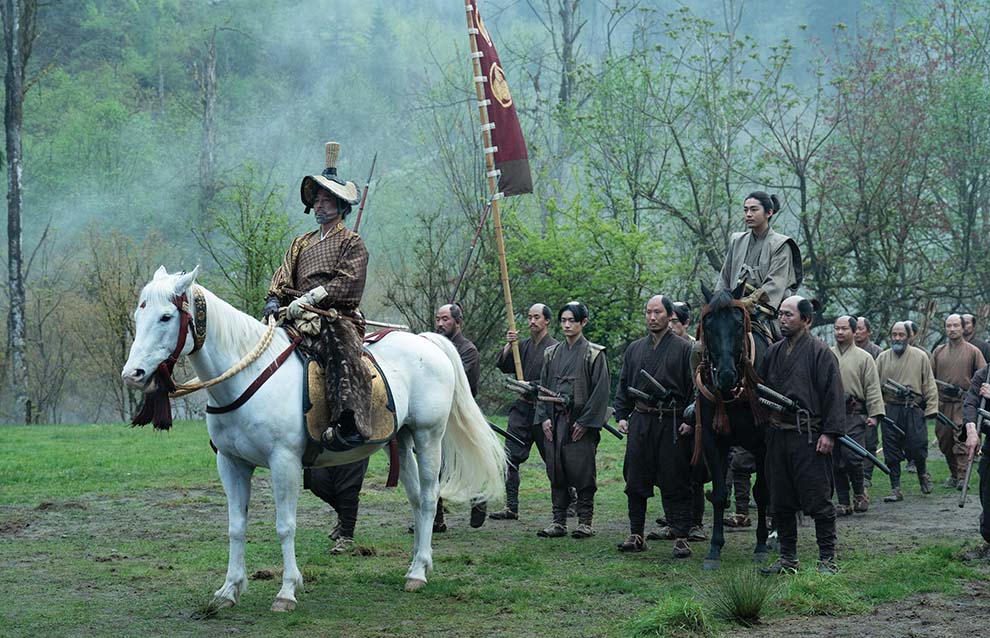 two people on horses followed by a group of soldiers