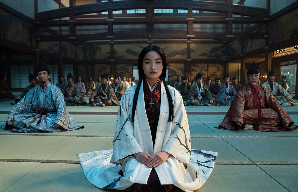 a person sitting in the middle of a room dressed in traditional Japanese garments