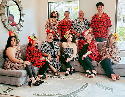 group of people wearing matching red outfits sitting on a couch inside a house