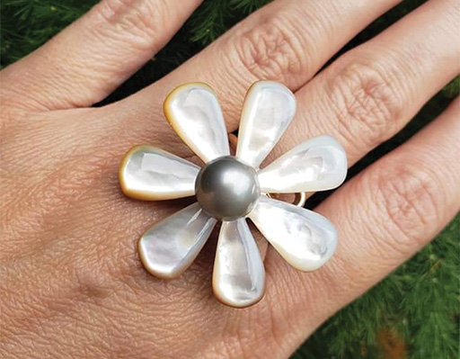 a closeup of a hand with a ring shaped like a flower